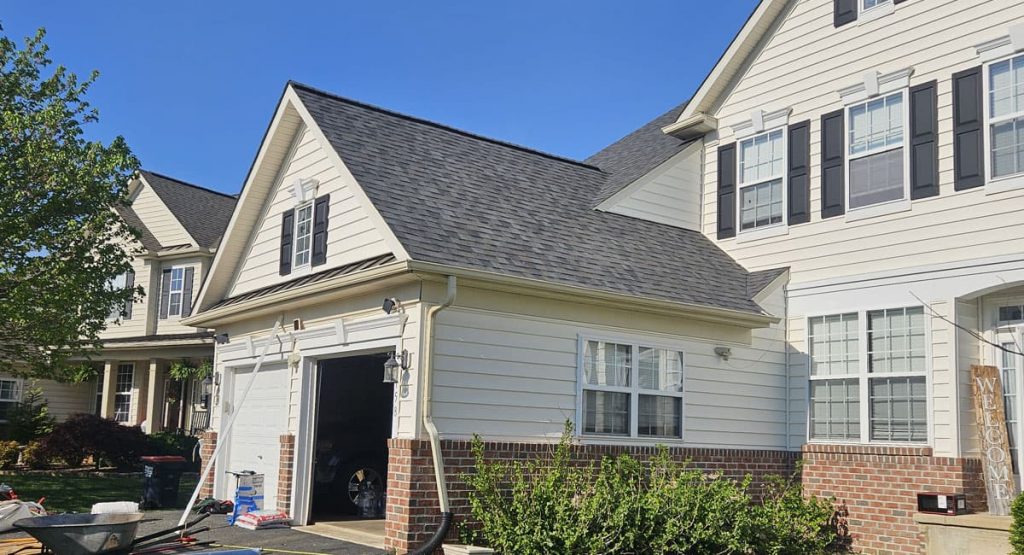 Front view of a beige townhome with brick base, open attached garage, and a clear blue sky behind it.